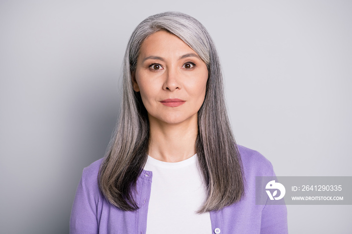 Portrait photo of an calm old lady with long white hair wearing purple cardigan isolated on grey col