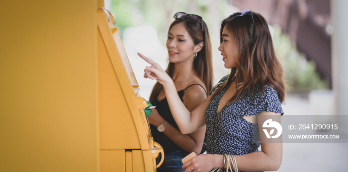 两名漂亮的亚洲女性使用ATM机从银行卡上取钱