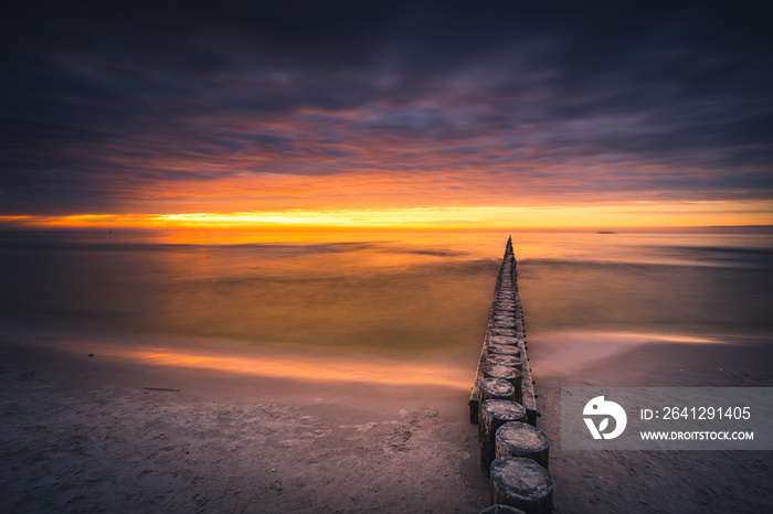 The Baltic breakwaters in Łeba with the setting sun. Long exposure photography.
