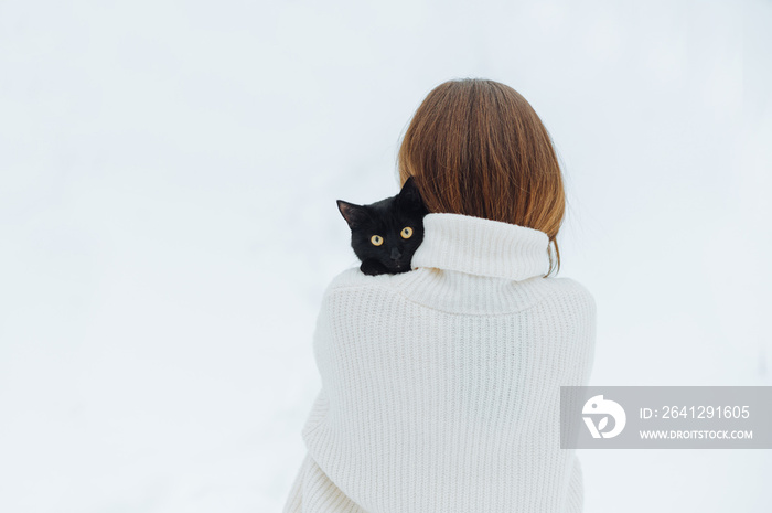 在白光中的女人背上，肩上扛着黑猫，宠物看着镜头。