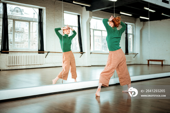 Young red-haired dance teacher with a hair bun looking artistic