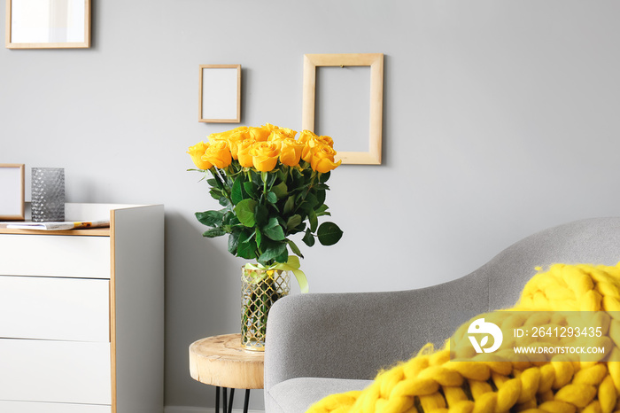 Vase with beautiful yellow roses on table in interior of room