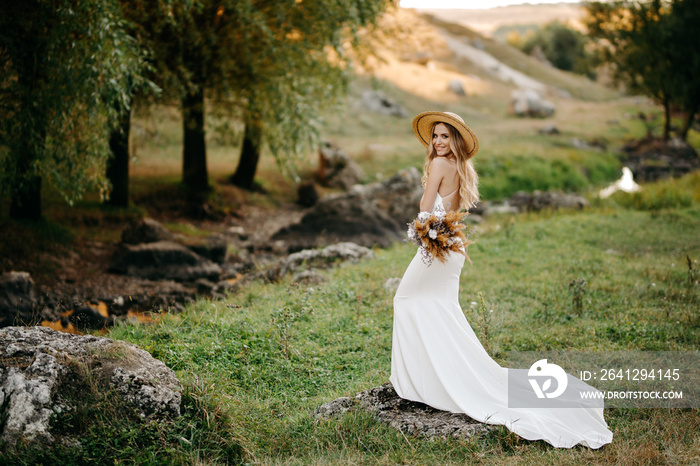 一个戴着帽子的美丽新娘，一个带着一束波西米亚风格花朵的新娘