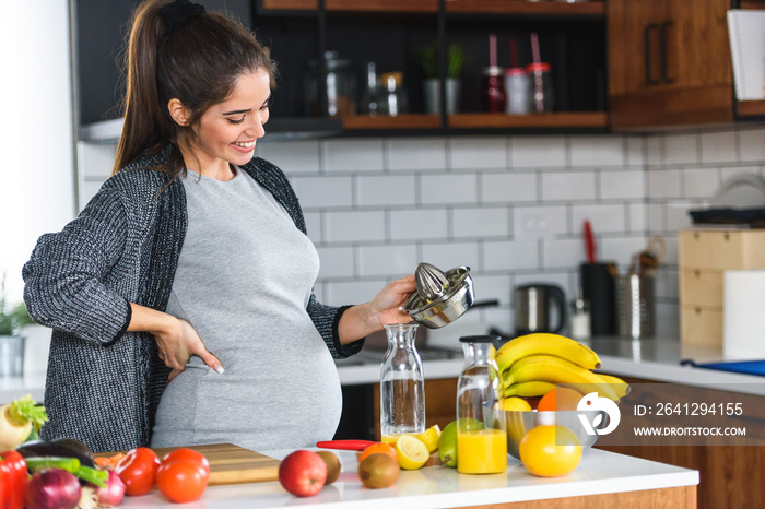 美丽微笑的年轻孕妇在h准备大量水果和蔬菜的健康食品