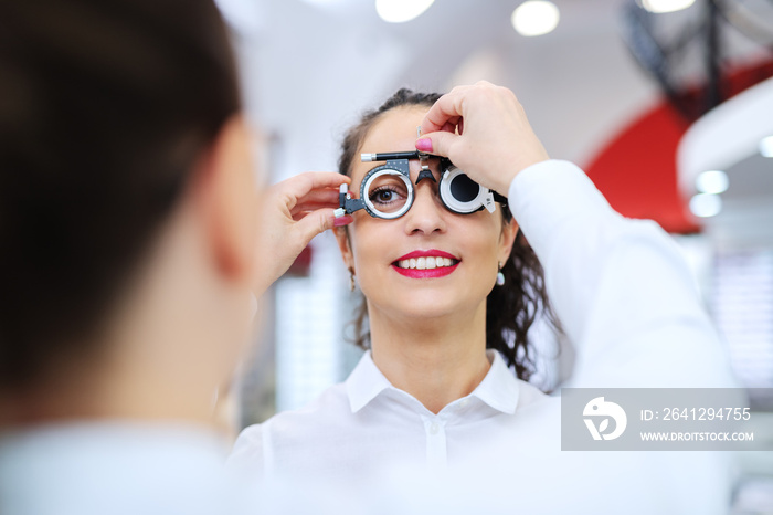 Young beautiful woman checking her sight at ophthalmologist. On eyes phoropter.