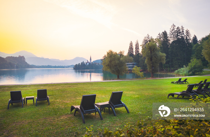 清晨，斯洛文尼亚流血的湖边，草地上有很多扶手椅，没有人。