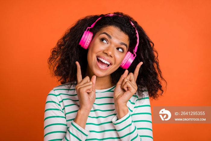 Photo of young lady listen music look up wear earphones shirt isolated on orange background