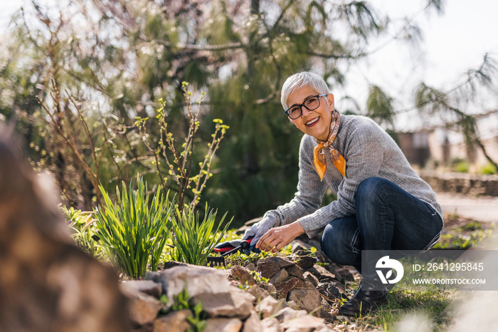 Portrait of a beautiful older woman cleaning up vegetable beds in the garden.