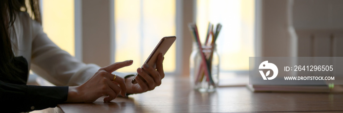 Side view of female freelancer using smartphone to relax form her work