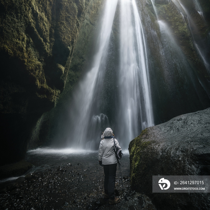 一个女人在冰岛的一个洞穴里看着Gljufrabui Waterdfall