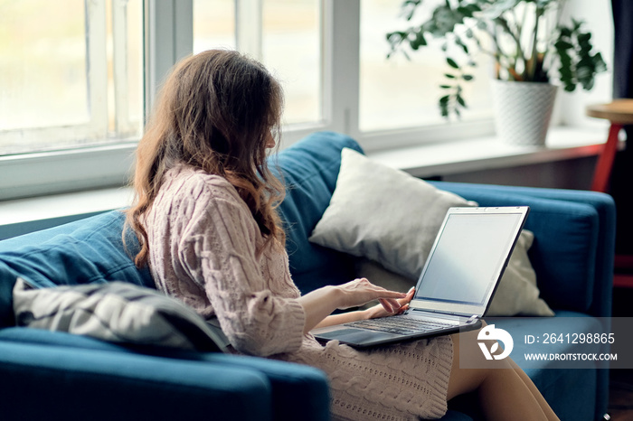 Smiling woman sitting with laptop on sofa in lounge