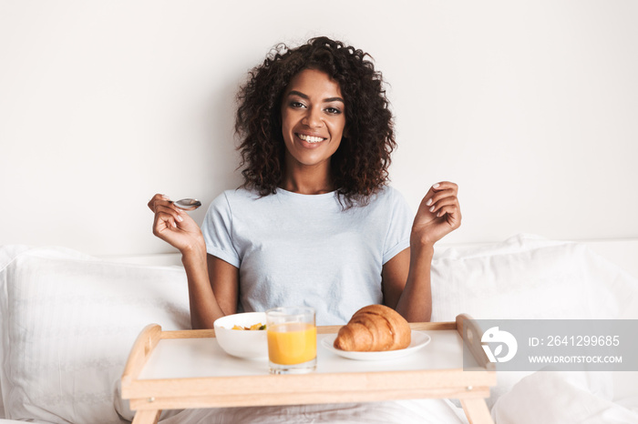 Happy young african woman having tasty breakfast