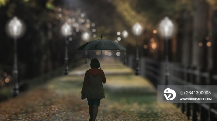一个撑着伞的女人晚上在雨中行走。