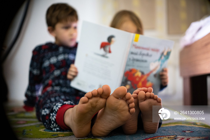 Brother and sister read book in pajamas bare feet evening sleep family