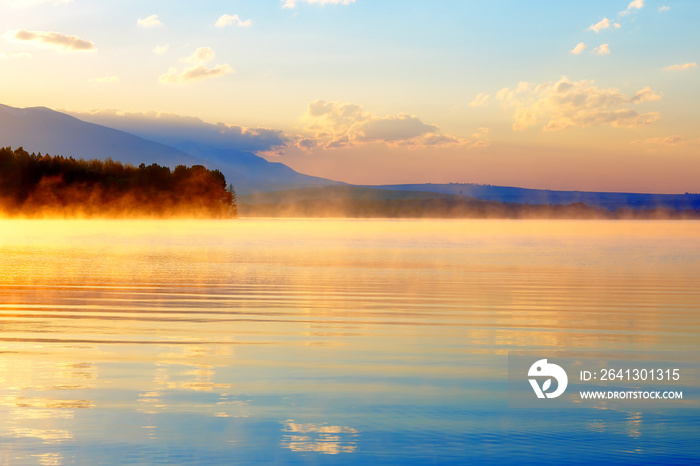 黎明时分，金蓝色和橙色色调的山脉和湖泊构成了美丽的景观。