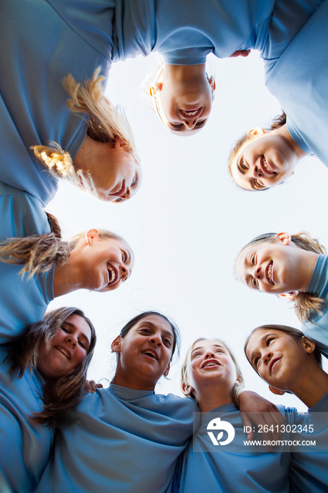 Low angle view of happy girls team huddling while standing against clear sky