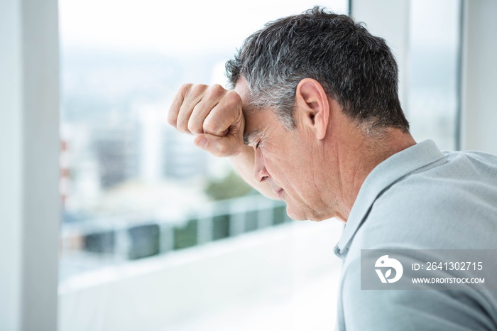 Tensed man leaning on glass window