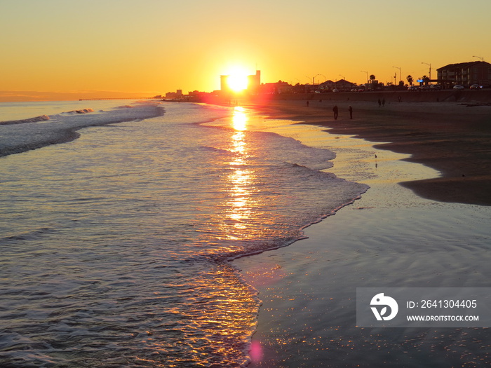 A gorgeous sunset in Galveston Island in Texas while waves gently wash ashore