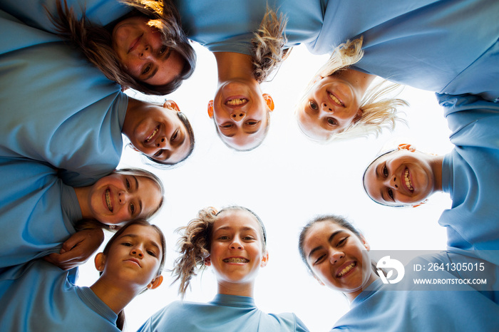 Low angle portrait of happy girls team huddling against clear sky