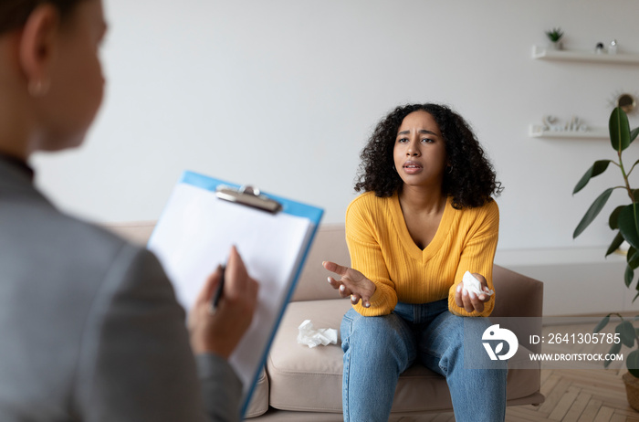 Psychotherapist giving consultation to depressed black female patient, having therapy session at cli