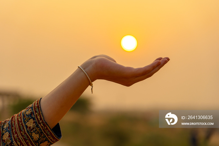 Silhouette of young girl holding the sun in hand during sunset, closeup