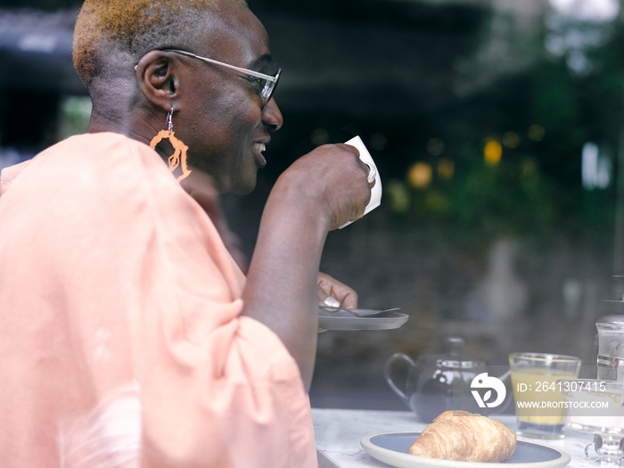 UK,ÊSmiling woman drinking coffee at breakfast table