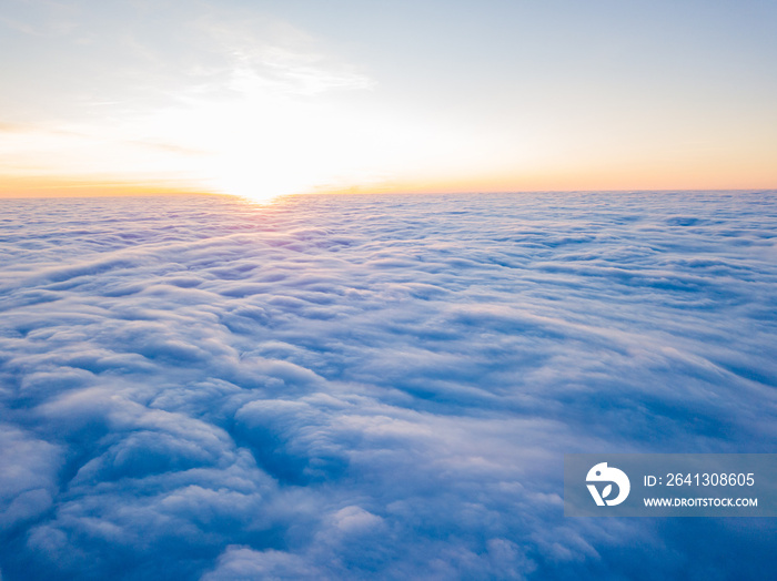 Sunset over curly clouds, aerial high flight. The last rays of the sun shine on the clouds.