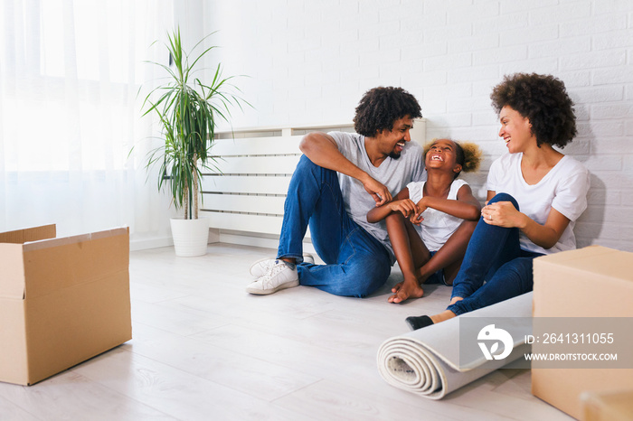 Young Happy African-american Family Unpacking after Move. Sitting on a Floor Resting at Their New Ho