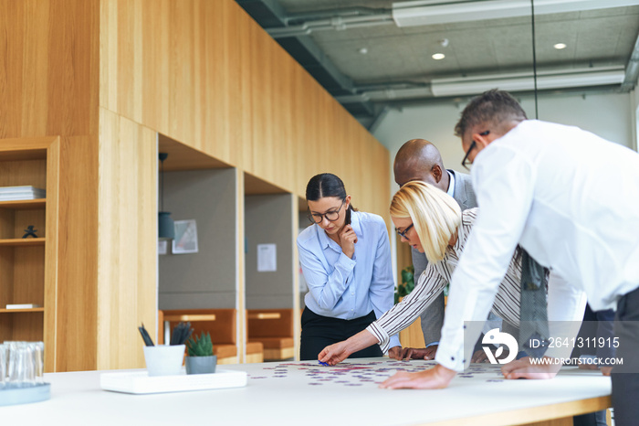 Diverse businesspeople trying to solve a puzzle in an office