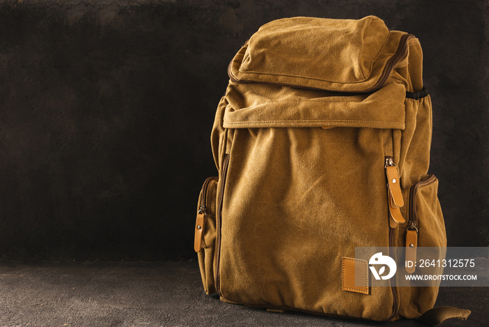 Hipster yellow backpack on table on dark background copy space