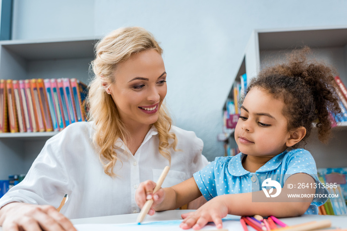 selective focus of cheerful woman looking at cute african american kid