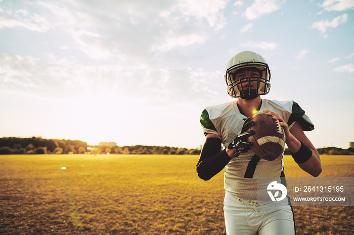 Young American quaterback standing alone on a football field