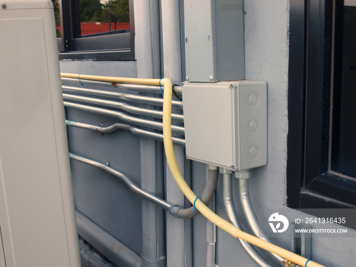 Closeup - White plastic electrical junction box and metal conduit on the wall of the building next t