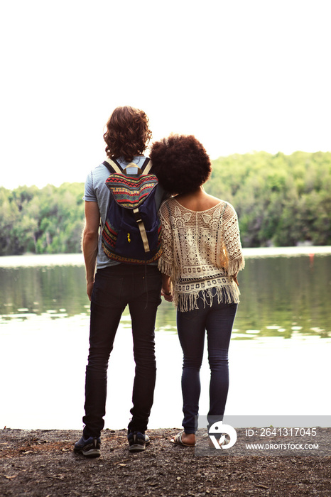 Couple looking at lake while standing on rock against clear sky