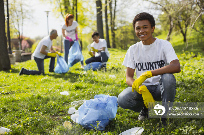 志愿服务问题。快乐的男志愿者在收集垃圾时对着镜头微笑
