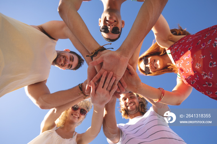 Group of friends forming hand stack on the beach