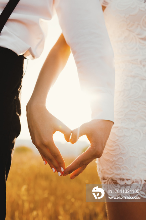 Close up of man and woman making heart with hands against bright