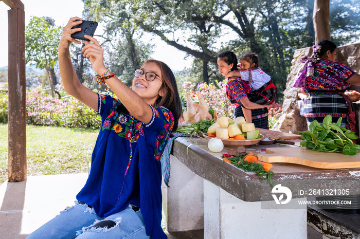 Chica haciendose una selfie con el telefono celular a ella su abuela y su mama. Familia cocinando al