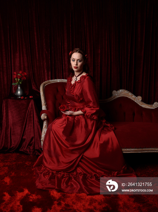 美丽的红头发女模特穿着迷人的维多利亚历史红色晚礼服的肖像。