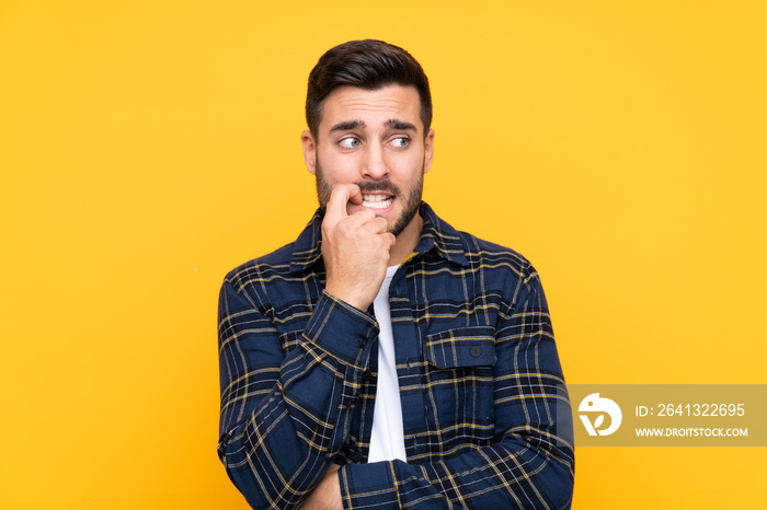 Young handsome man with beard over isolated yellow background nervous and scared