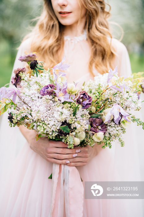 新娘穿着漂亮的粉色连衣裙，手里拿着一束野花。特写