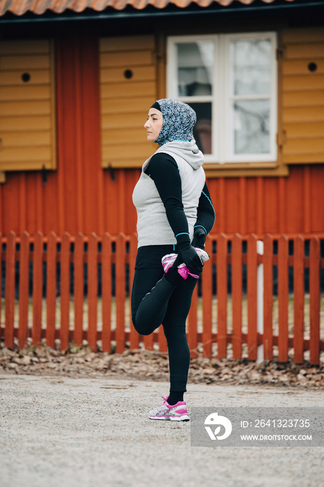 Full length of confident jogger stretching leg while exercising on street