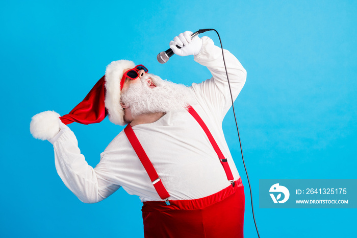 Photo of old man grey beard hold mic open mouth sing song wear santa claus x-mas costume headwear su