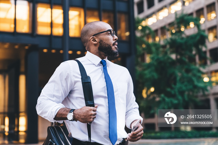 Elegant black boss looking away with smartphone