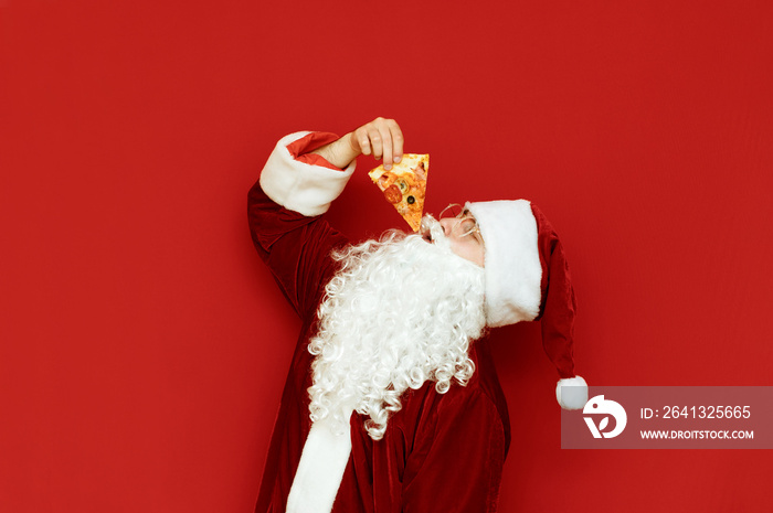 Hungry Santa Claus with white beard eating pizza slice on red background. Santa loves to eat pizza, 