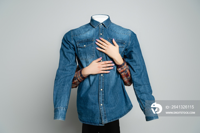 cropped view of woman embracing mannequin in blue denim shirt on grey