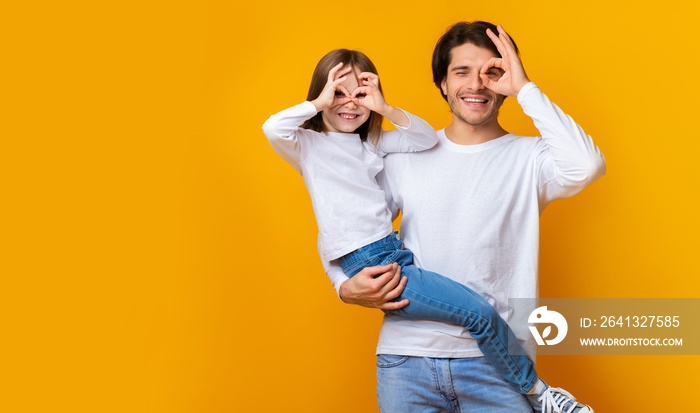 Joyful dad and daughter having good time over yellow background