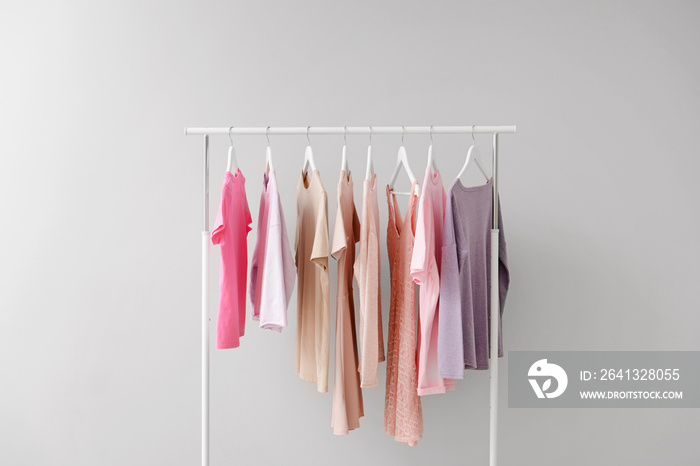 Rack with clothes after dry-cleaning on light background