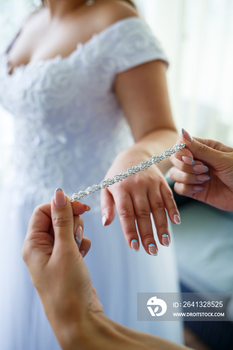 bride puts on wedding jewelry on the wedding day