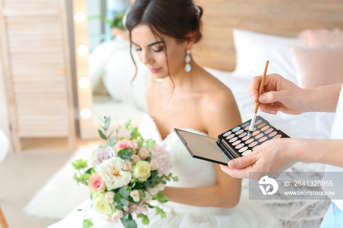 Professional makeup artist working with young bride at home